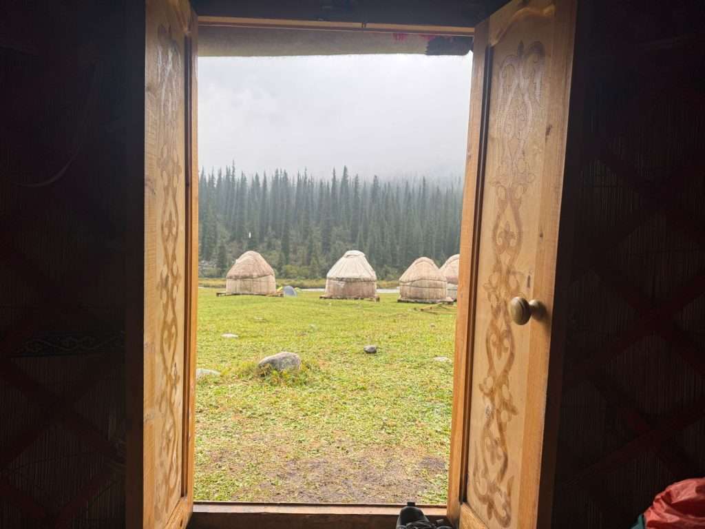Multiple yurts are seen from the inside of a yurt, through traditional doors.