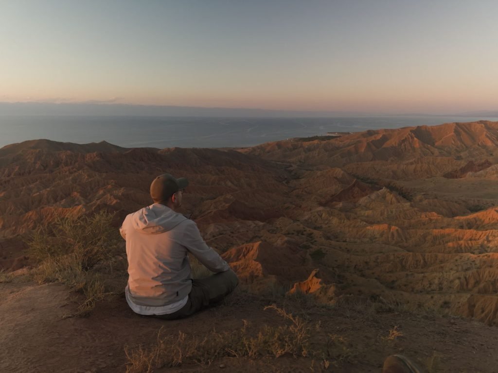 Back of a man sitting on a cliff at Skazka Canyon