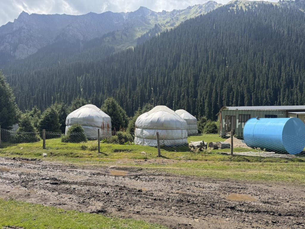 Three traditional Kyrgyzstani yurts by a dirt road in Altyn Arashan